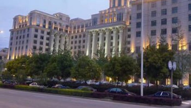 A large, multi-story building with classical architecture, featuring columns and a dome.