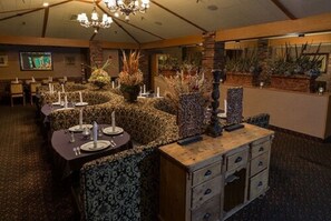 Un restaurante con tapicería estampada, un candelabro y una pared de acento de piedra.