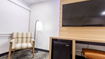 A room with a chair, a desk with a small black refrigerator, a lamp, and a large blackboard on the wall.