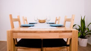 Una mesa de comedor de madera con cuatro sillas, un posavasos blanco y platos azules.