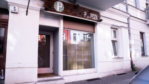 Un edificio con un letrero que dice “PIZZA” y el número “5” en la pared.
