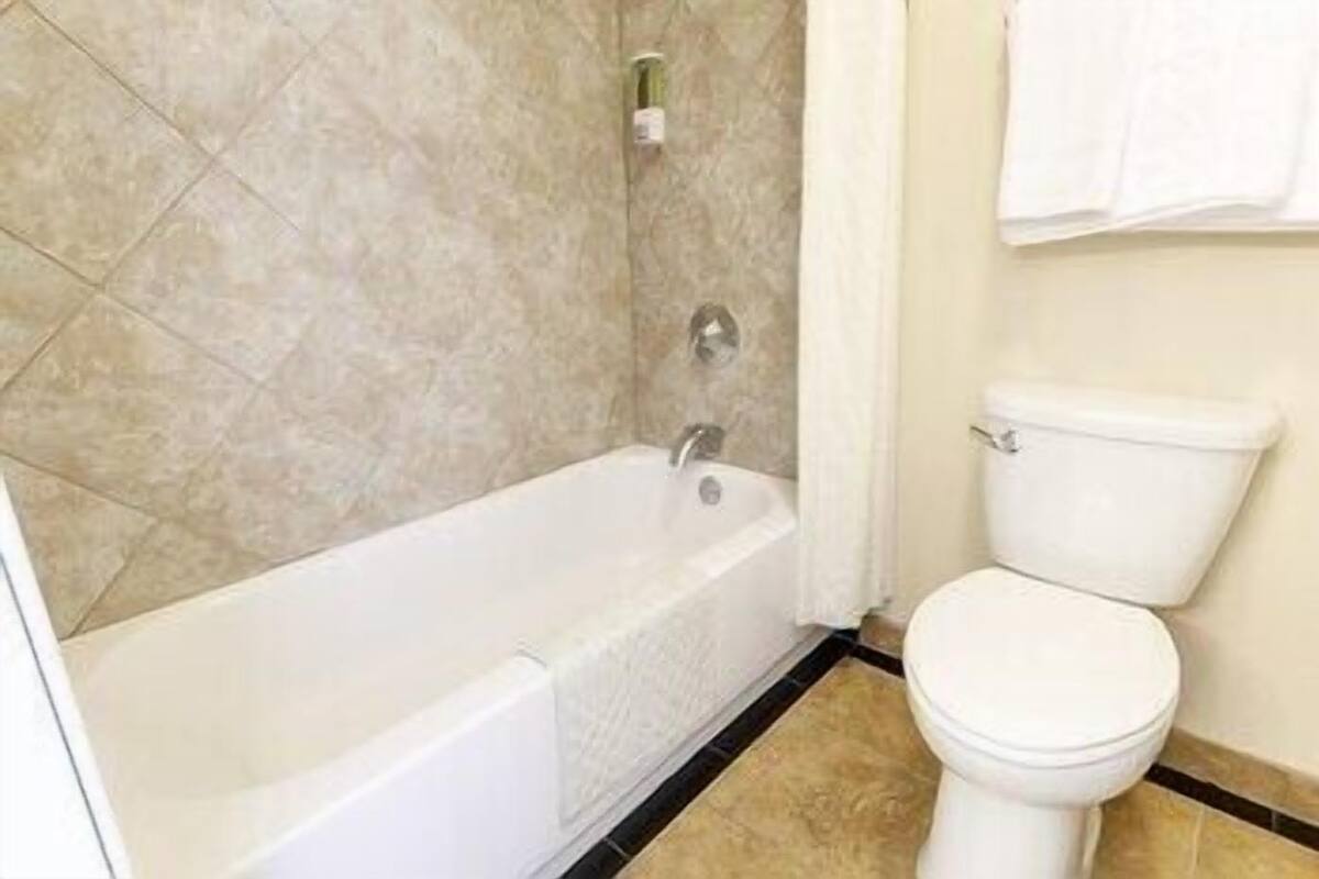 Un baño con bañera, inodoro y paredes con azulejos.