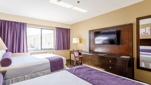 Une chambre d’hôtel avec deux lits, une télévision, un bureau et une fenêtre avec des rideaux.