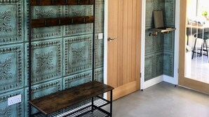 A room with patterned wallpaper, a wooden door, a bench, and a hanging light fixture. - Meadowsweet Barn, Ashlin Farm Barns (Lincoln)