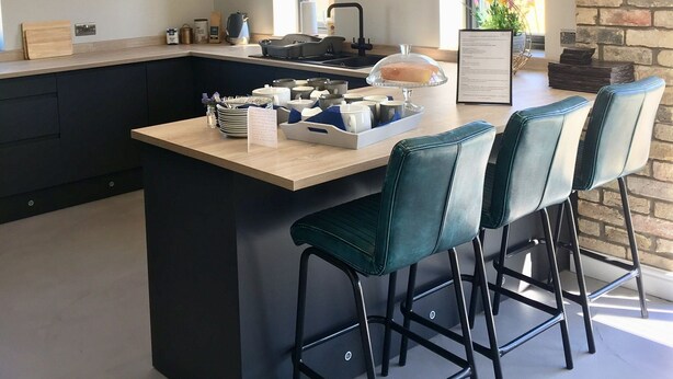 A modern kitchen with a central island, bar stools, pendant lighting, and a decorative wall clock. - Meadowsweet Barn, Ashlin Farm Barns (Lincoln)