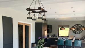 A modern kitchen with a wooden table and benches, a clock, and a vase with flowers. - Meadowsweet Barn, Ashlin Farm Barns (Lincoln)