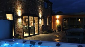 A hot tub area with a brick house in the background. - Meadowsweet Barn, Ashlin Farm Barns (Lincoln)