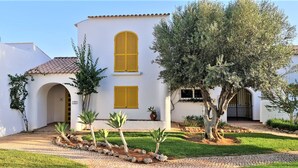 A white building with yellow shutters, a tiled roof, and a paved entrance. - Aldeia do Golf- Family with Pool and Wi-fi (Vilamoura)
