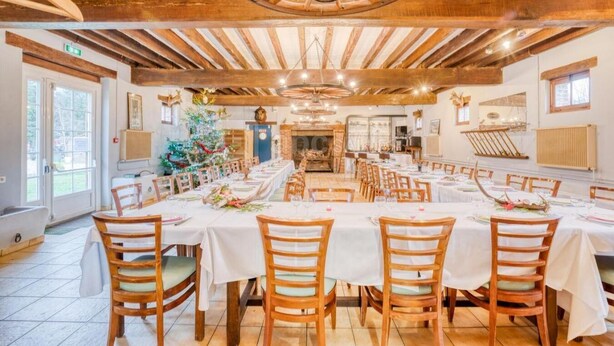A large dining hall with wooden beams, white tablecloths, and wooden chairs. - Auberge de villechaume (Sennely)