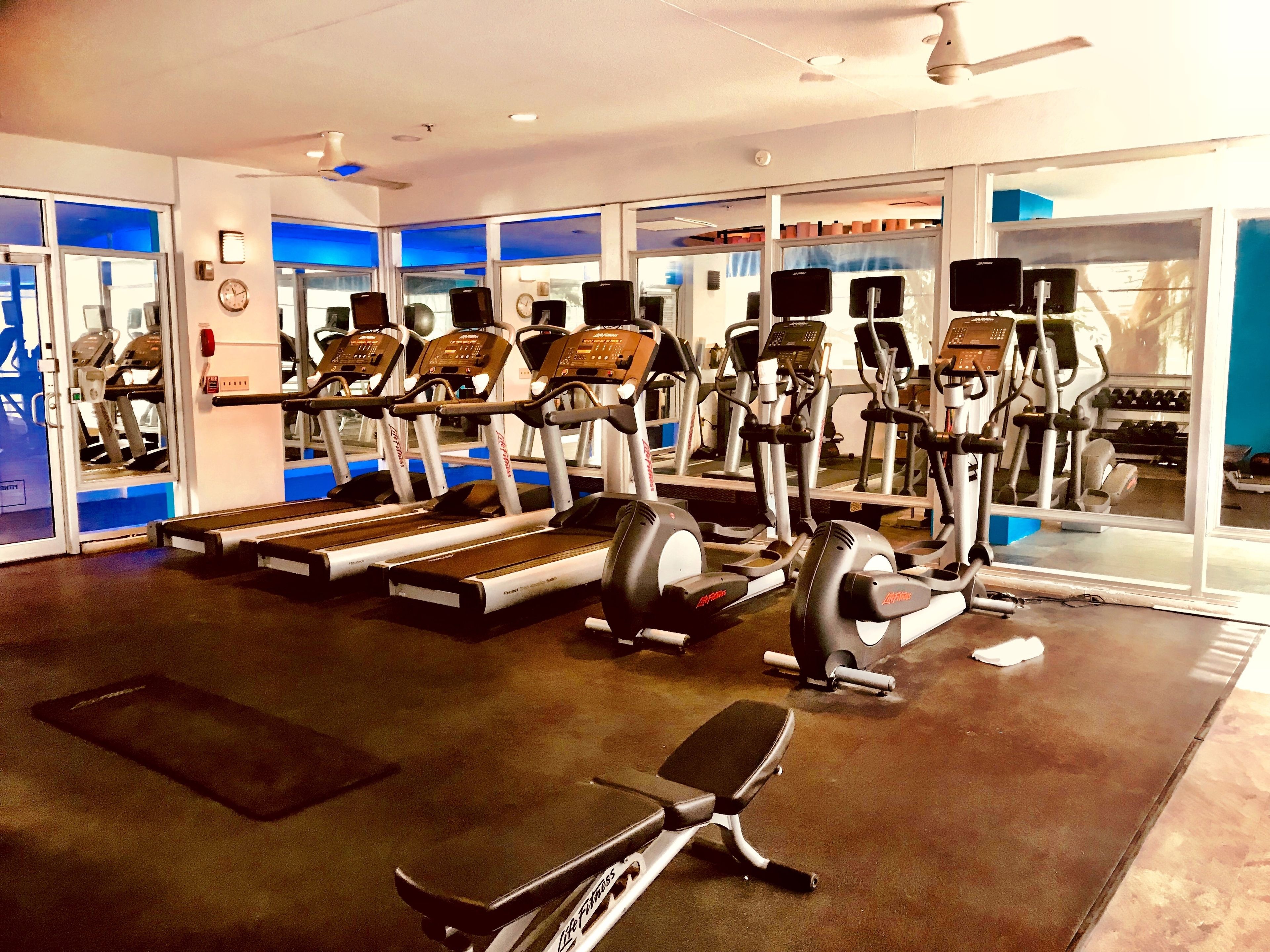 Una palestra con tapis roulant, ellittiche e una panca.