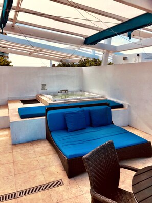 An outdoor seating area with a hot tub, blue cushions, and wicker furniture. - De Soleil Hotel on Ocean Drive (Miami Beach)
