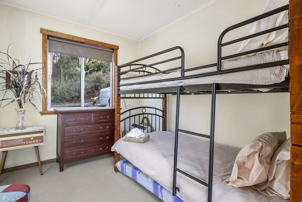A bunk bed room with a dresser, a window, and a desk.
