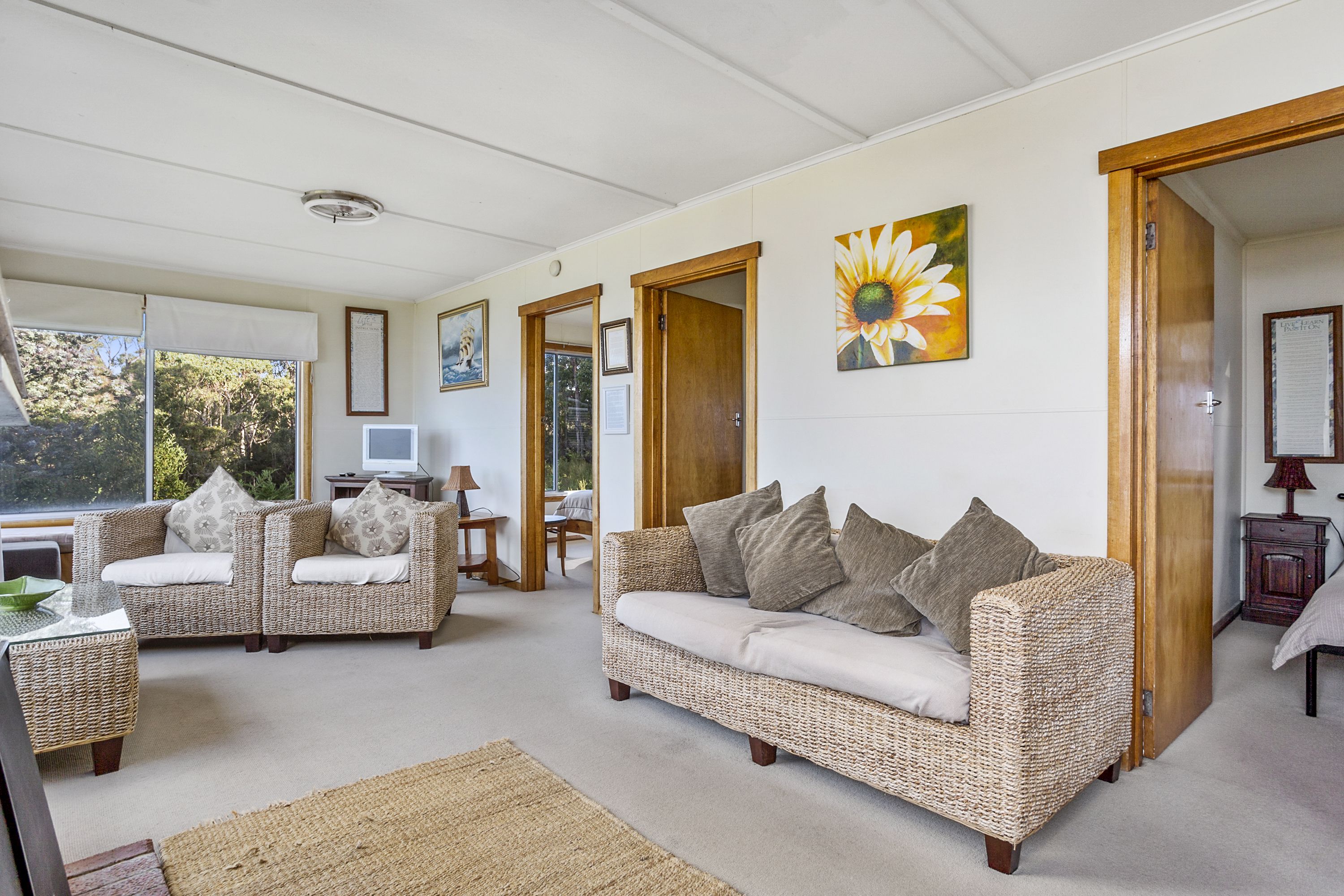 A spacious living room with two wicker sofas, a coffee table, and a large window providing a view of the outdoors.
