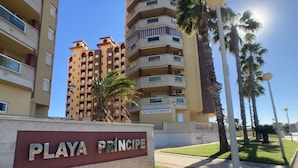 Een bord met daarop Playa Princesa, met een gebouw op de achtergrond.