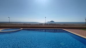 Een helderblauw zwembad met uitzicht op zee en een eiland in de verte.
