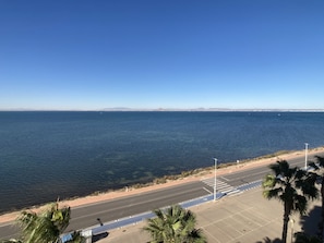A coastal road with a clear view of the ocean and distant mountains.