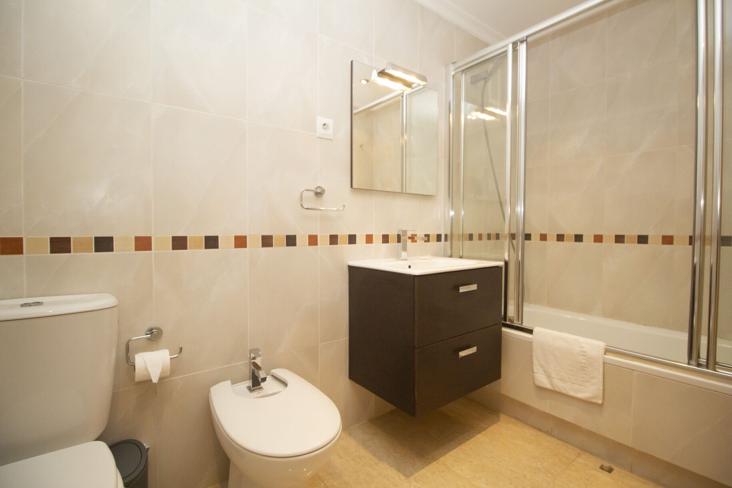 A modern bathroom with a toilet, sink, vanity, and shower.