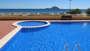 Une piscine avec vue sur l’océan et une île lointaine.
