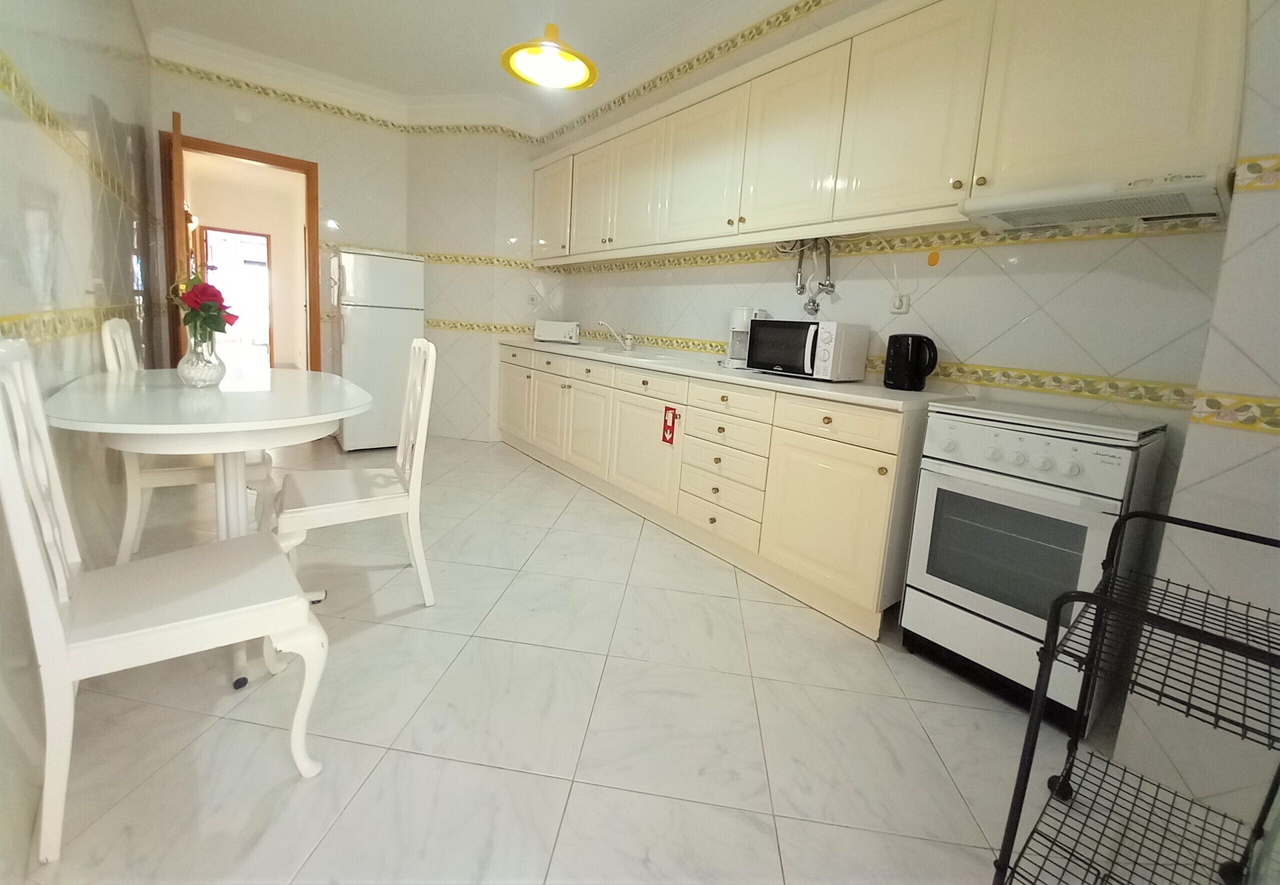 A kitchen with white cabinets, a microwave, an oven, and a dining table with chairs.