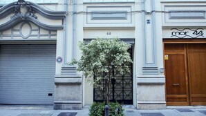 A building with a number 44 sign, a closed garage door, and a wooden door with a sign above it. - Singular Stays Mar44 I (Valencia ciudad)