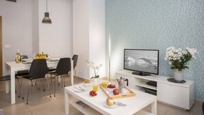 A modern dining area with a white table set for breakfast, a television, and a decorative plant. - Singular Stays Mar44 I (Valencia ciudad)