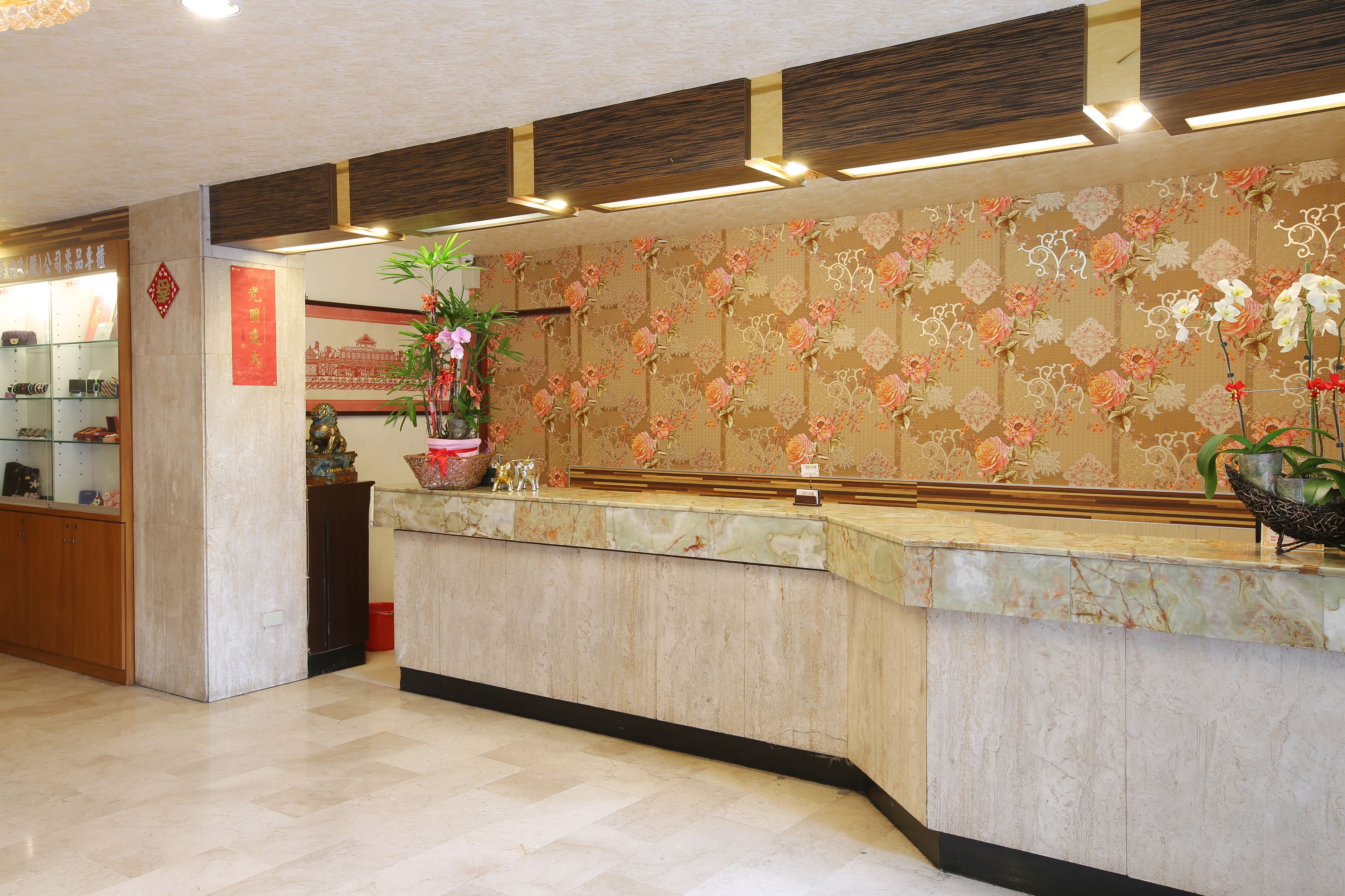 A reception area with a marble counter, floral wallpaper, and a display of local crafts.