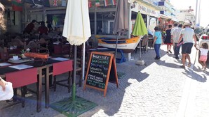 Un área de comedor al aire libre con mesas, sillas, un bote y un menú en una pizarra.