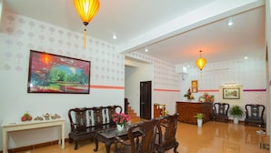 A spacious lobby with a reception desk, seating area, and a large painting on the wall. - Cua Dai Beach Homestay (Da Nang)