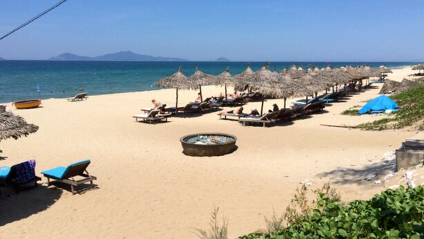 A beach with thatched umbrellas, lounge chairs, and a small pool. - Cua Dai Beach Homestay (Da Nang)