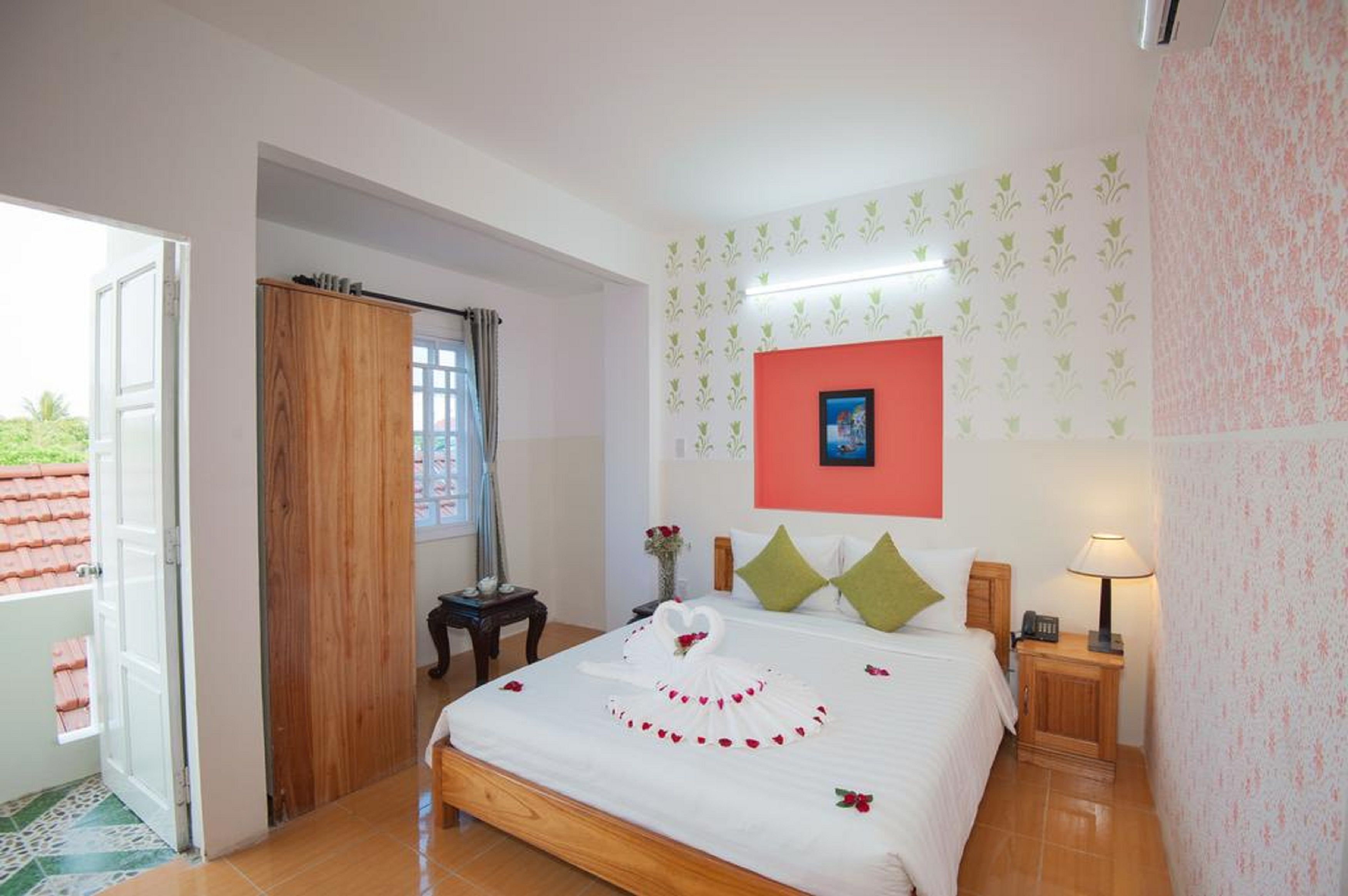 A hotel room with a bed, a nightstand, a lamp, a picture on the wall, and a door leading to a balcony.