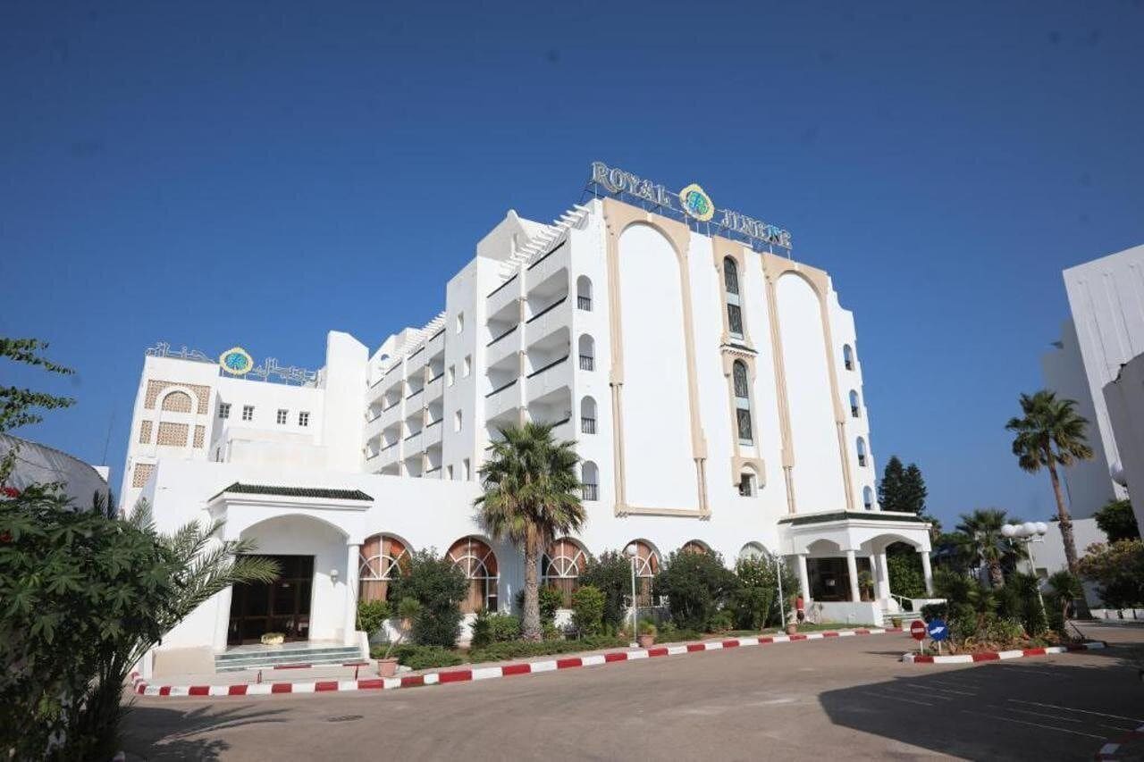 Un hotel blanco con balcones y una entrada central, con un letrero que dice "ROYAL HOTEL".