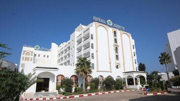 Un hotel blanco con balcones y una entrada central, con un letrero que dice "ROYAL HOTEL".