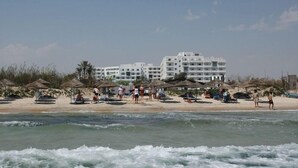 A beachfront hotel with multiple balconies, beach umbrellas, and a sandy beach. - Hotel Royal Jinene (Sousse)