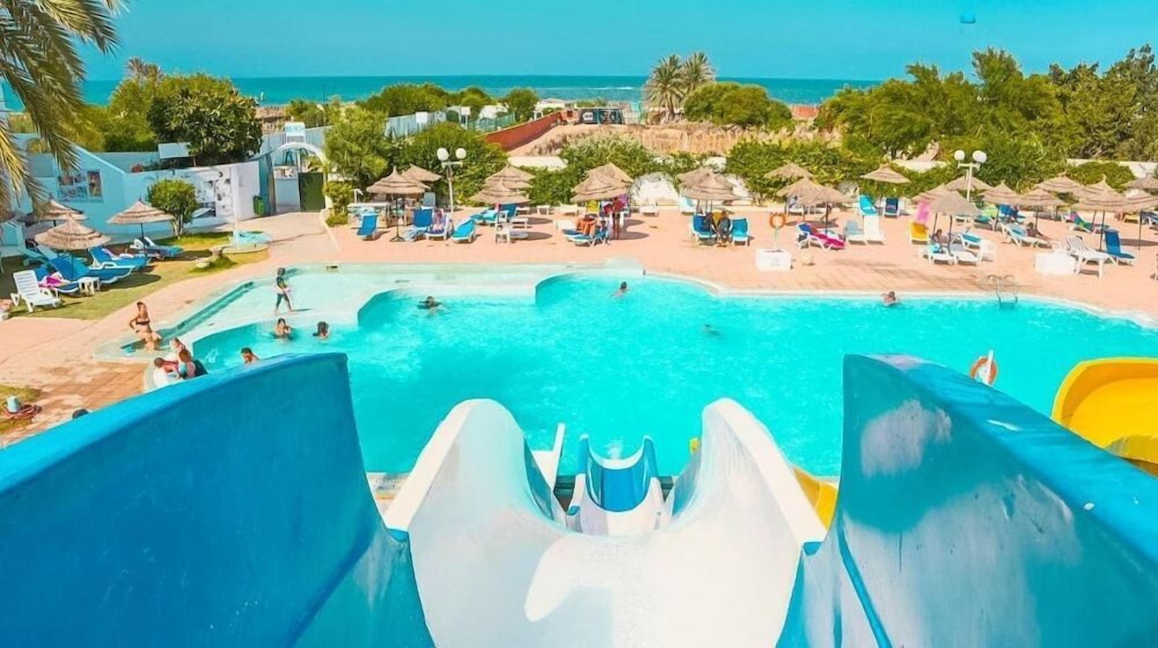 Parque acuático con una piscina grande, toboganes y zona de playa.