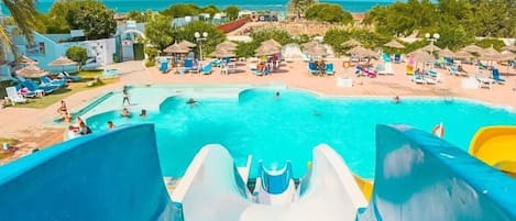 Parque acuático con una piscina grande, toboganes y zona de playa.