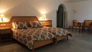 A bedroom with a bed, two bedside lamps, a chair, and a door.