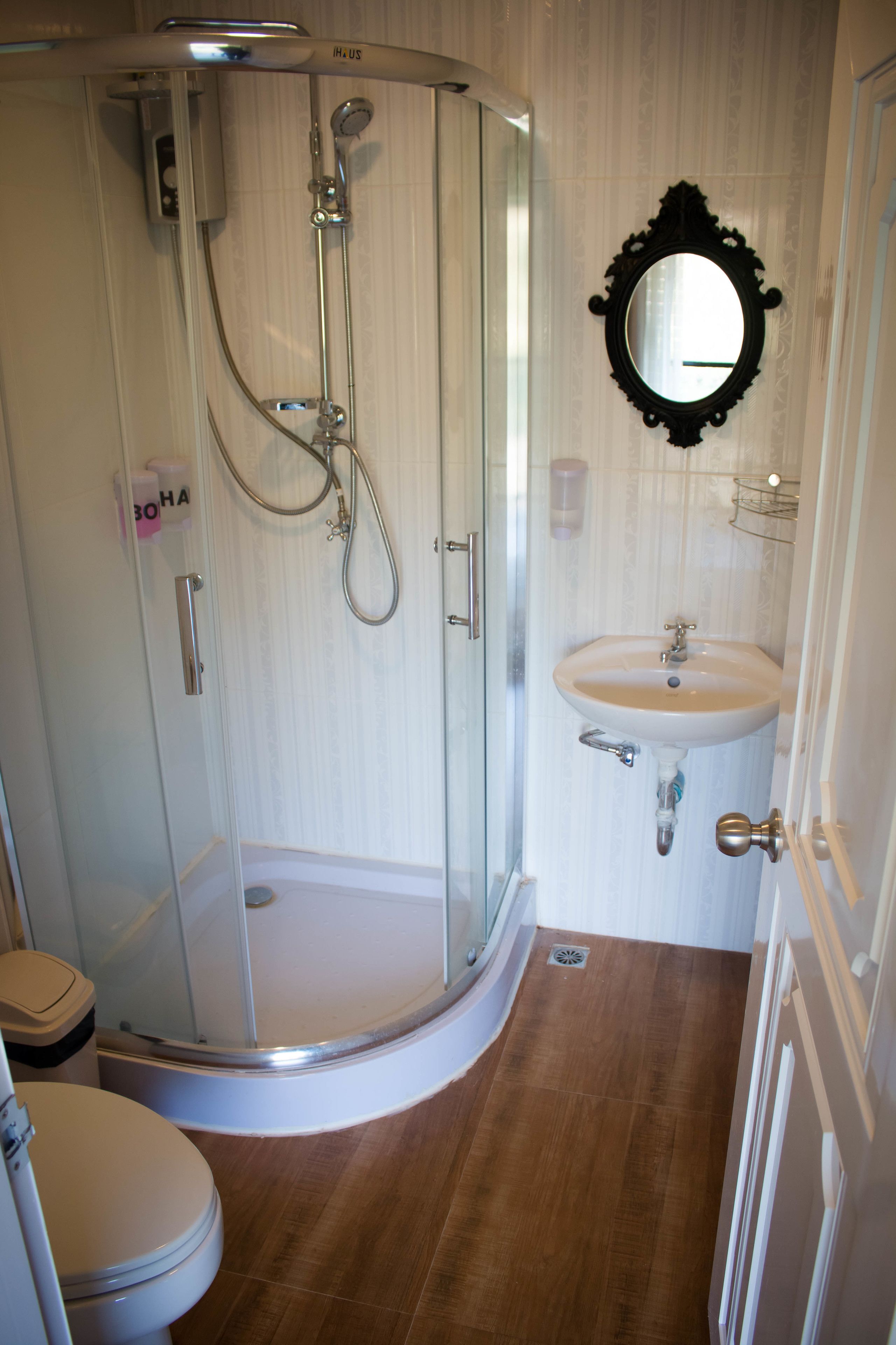 A bathroom with a glass-enclosed shower, a sink, and a mirror.
