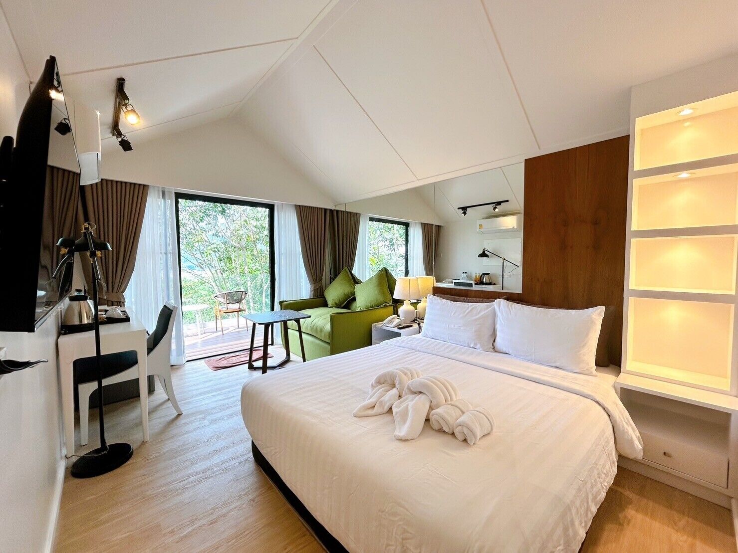 Ein modernes Hotelzimmer mit einem großen Bett, einem Schreibtisch, einem Sessel und einer Couch.