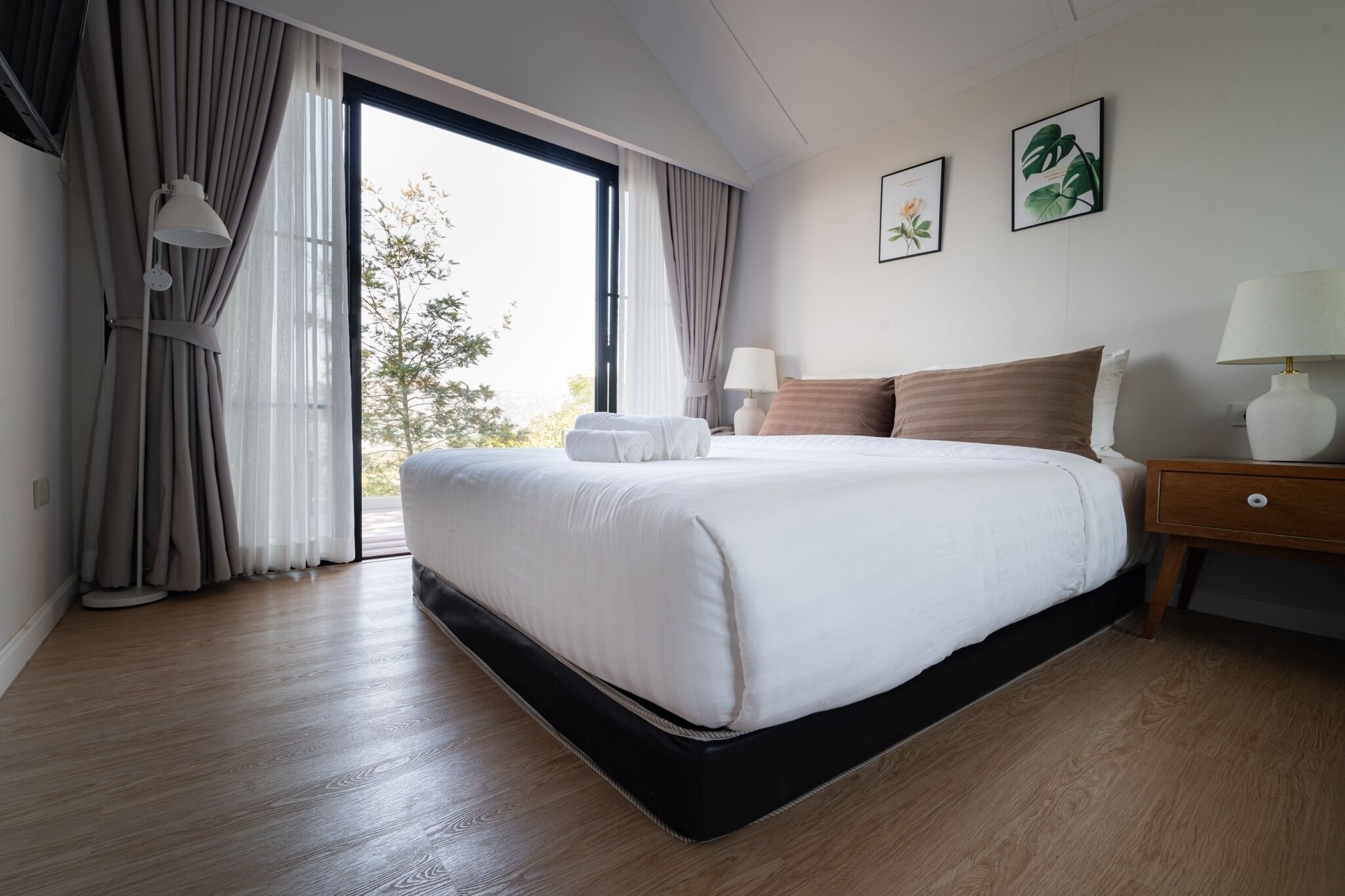 Una camera da letto con un letto grande, un comodino, una lampada e vista sull'esterno.