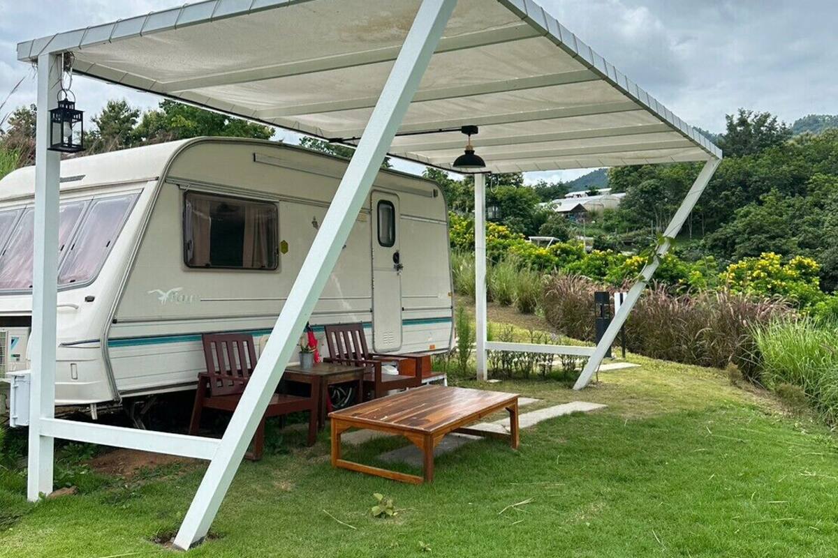 A caravan with a covered patio area, a table, and chairs.