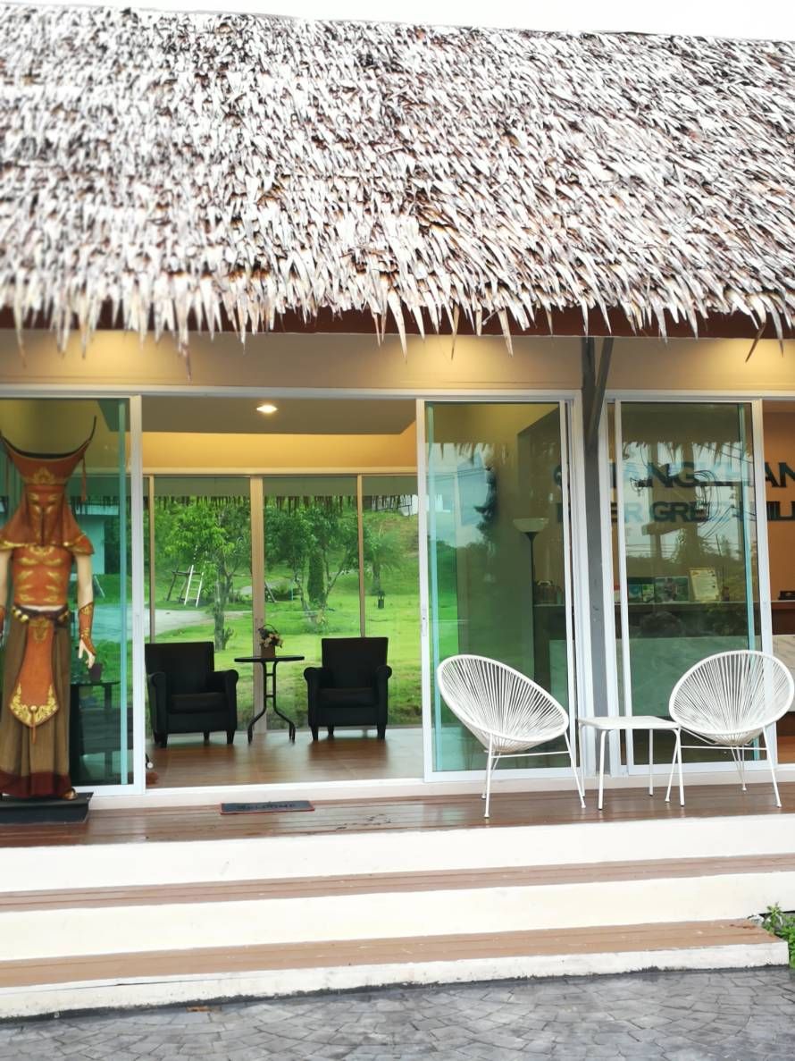 A modern building with a thatched roof, large glass windows, and a statue outside.