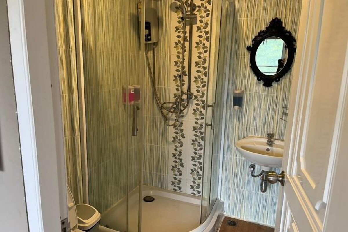 A bathroom with a glass-enclosed shower, a sink with a mirror, and a toilet.