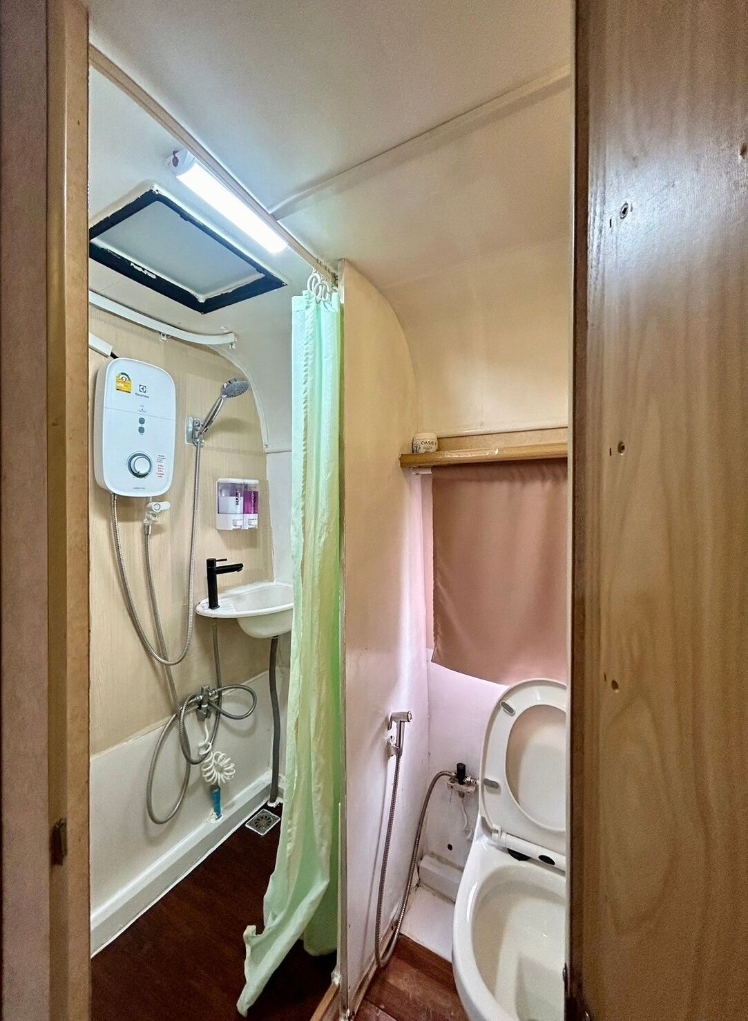A compact bathroom with a shower, toilet, and a small sink.