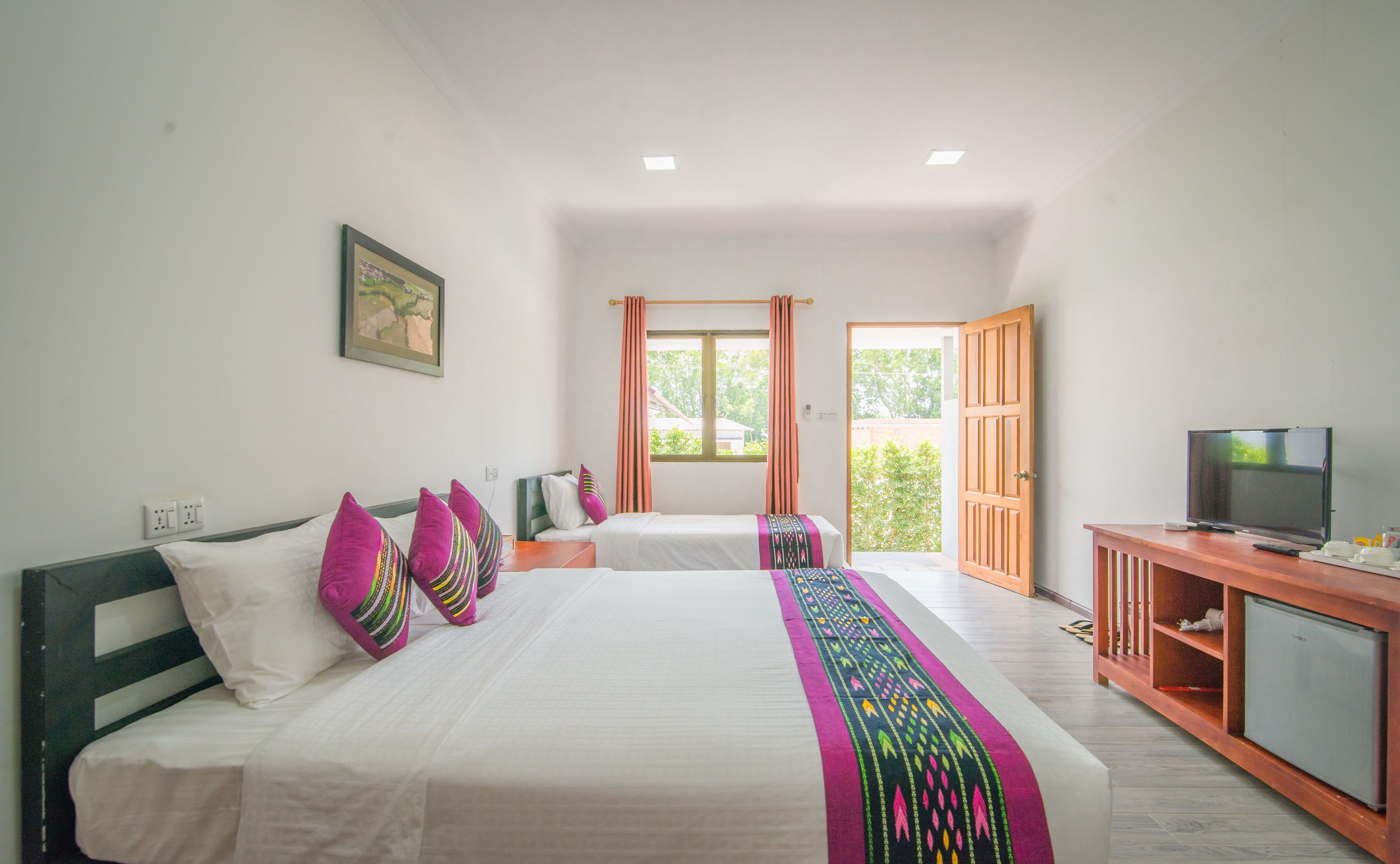 A bedroom with two beds, a television, and a small refrigerator.