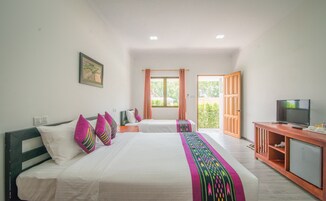 Un dormitorio con dos camas, televisor y un refrigerador pequeño.