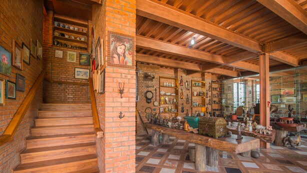 A rustic interior with wooden stairs, brick walls, and a variety of displayed items.
