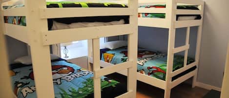 A room with bunk beds, each with a colorful bedspread featuring cartoon characters.