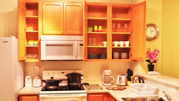 Una cocina compacta con armarios de madera, microondas, estufa y varios electrodomésticos.