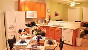 Una cocina con armarios de madera, un microondas, una estufa y una zona de comedor con una mesa para dos.