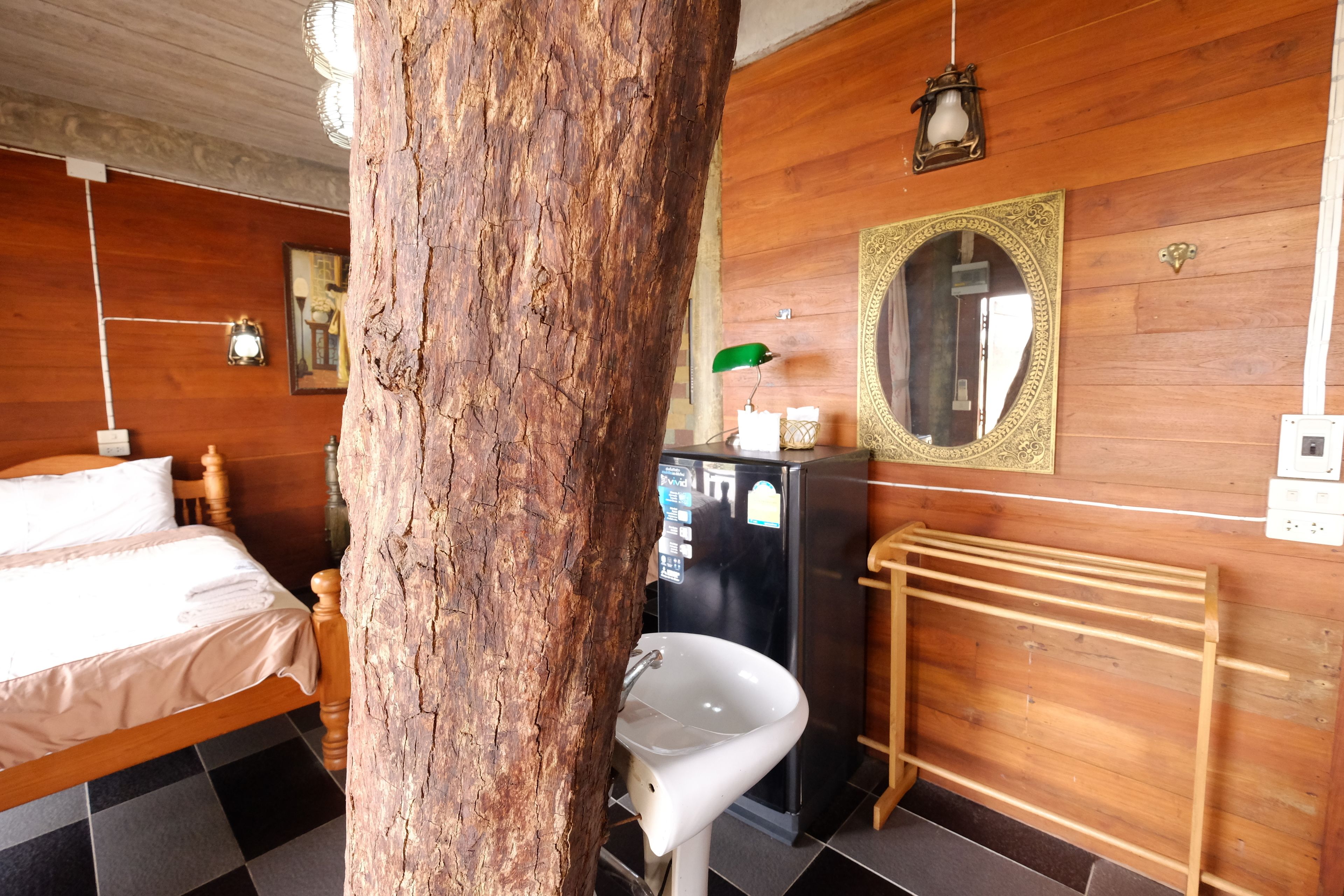 Una habitación con una cama de madera, un lavabo blanco, un espejo y un radiador.